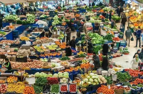 Tomatoes, onions and greens laid out on a produce stall